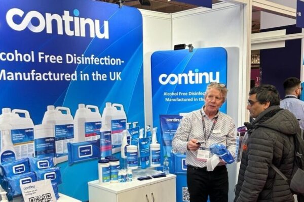Sales man stands in front of exhibition booth at Therapy Expo to sell Continu Disinfection to a visitor