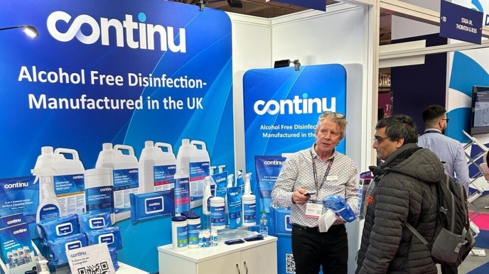 Sales man stands in front of exhibition booth at Therapy Expo to sell Continu Disinfection to a visitor